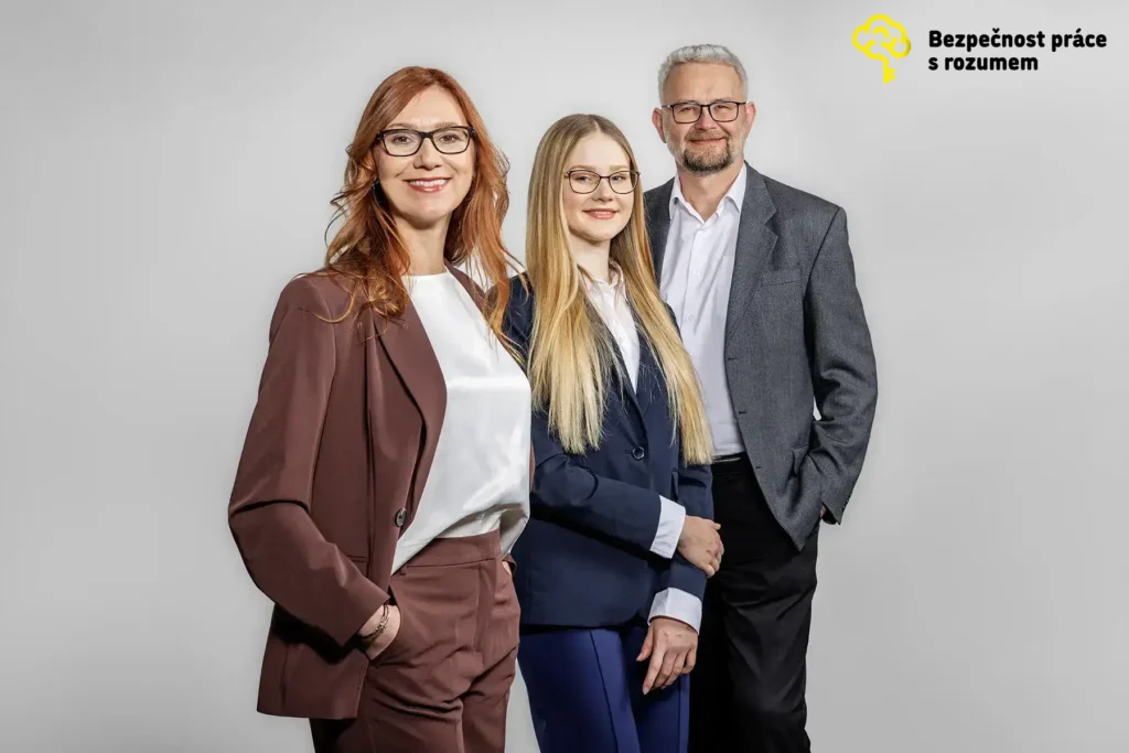 Tři lidé v business oblečení pózují před světlým pozadím s logem Bezpečnost práce s rozumem.