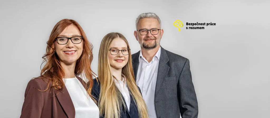 Tři profesionálně oblečení lidé pózují před světlým pozadím s logem Bezpečnost práce s rozumem.
